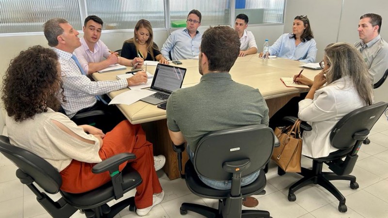 Várias pessoas em reunião, sentadas em volta de uma mesa.